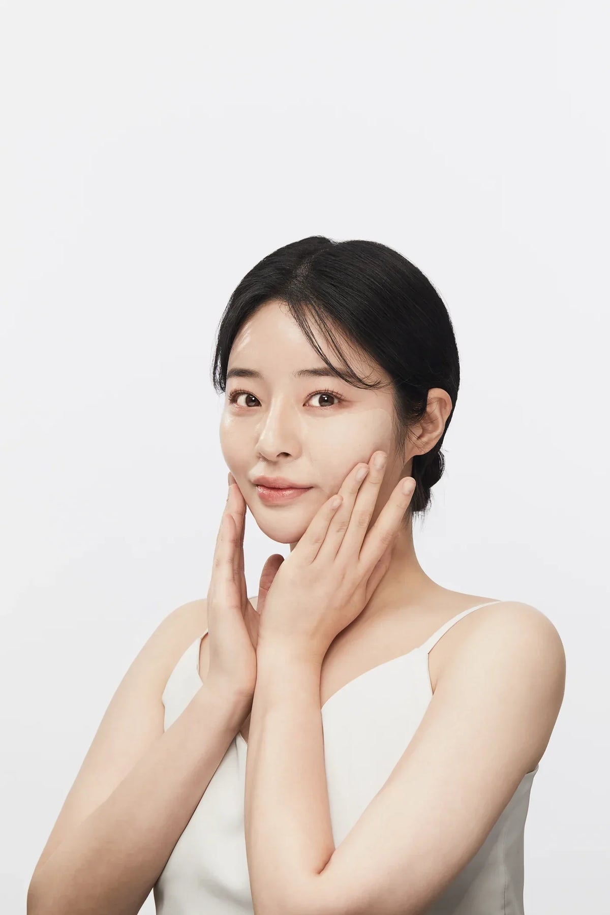 A woman in a white top touching her cheek, VVBETTER editorial portrait
