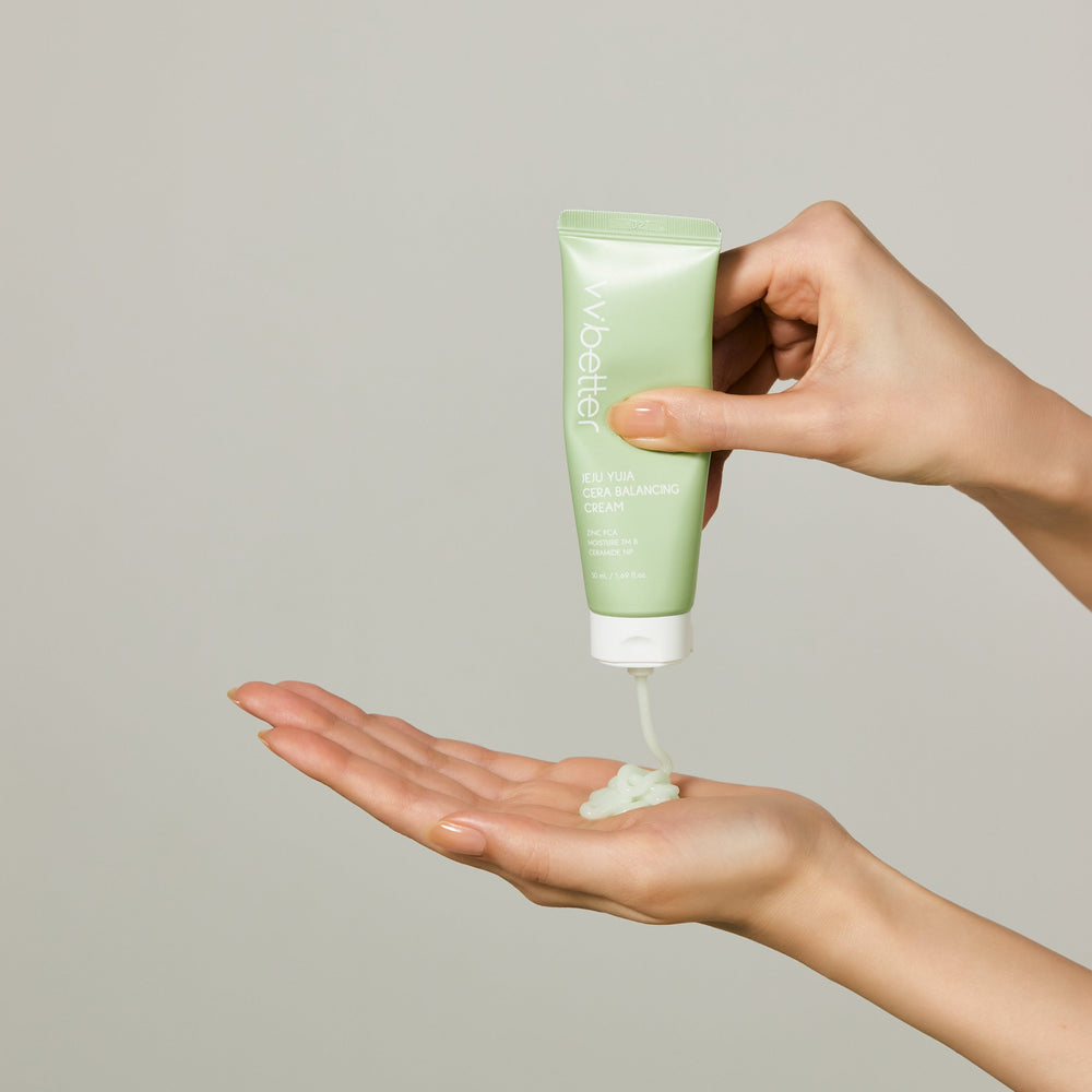 Hand squeezing Jeju Yuja Cera Balancing Cream from a light-green tube into the palm