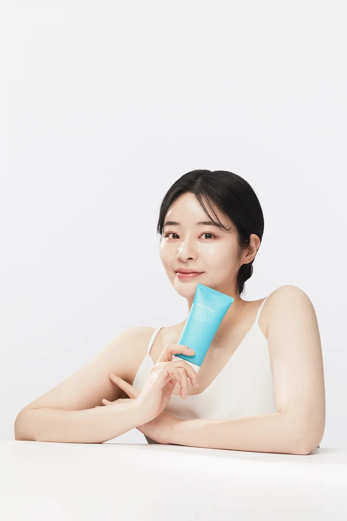 A woman holding a blue 5.5 Soothing Cleansing Foam tube, VVBETTER studio photograph