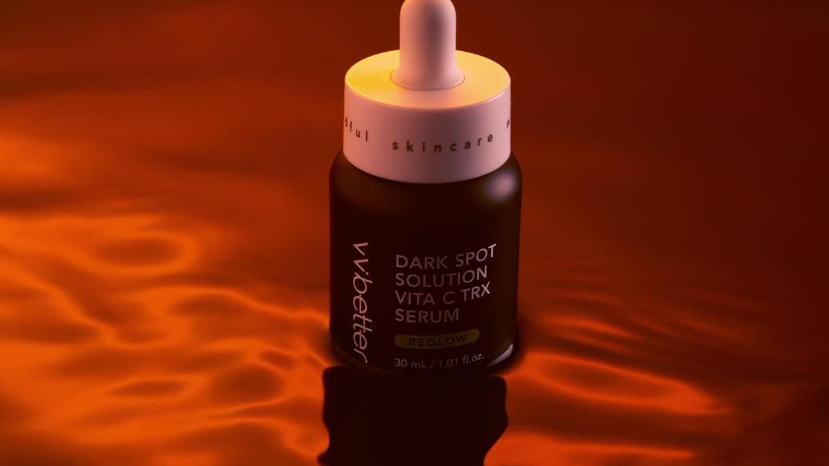 Dark Spot Solution Vita C TRX Serum bottle with a dropper cap, standing in rippled orange light