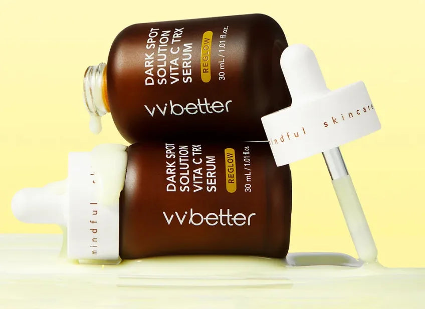 Two amber glass bottles of Dark Spot Solution Vita C TRX Serum with white droppers on a yellow background