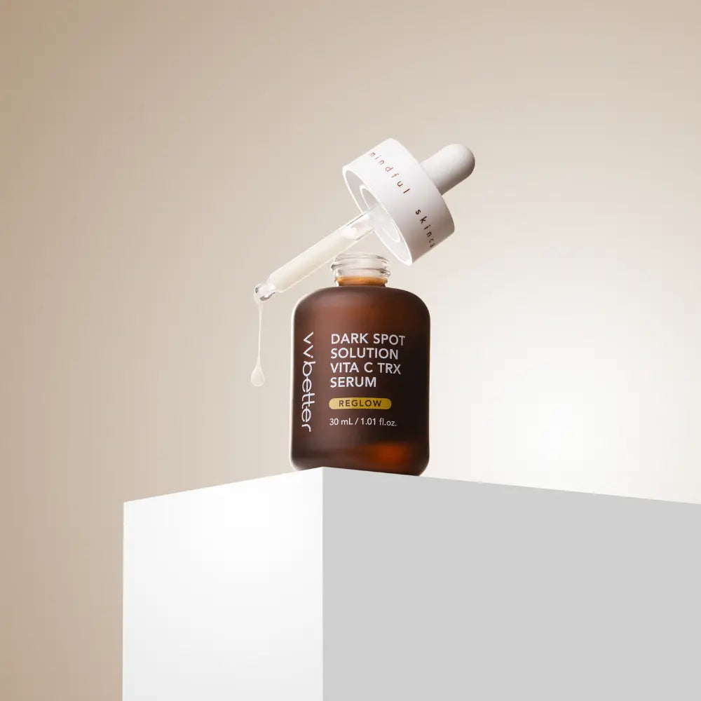 Dark Spot Solution Vita C TRX Serum — bottle on a white pedestal with the dropper lifted, beige backdrop