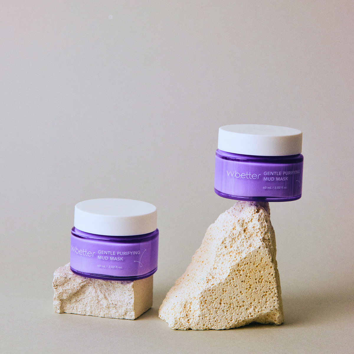 Gentle Purifying Mud Mask — two jars set on pale stone blocks, angle view