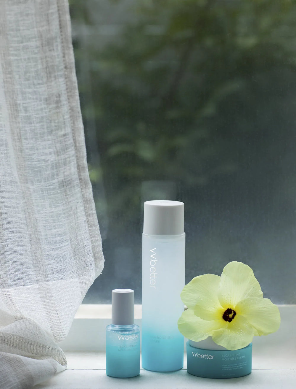 The Blue Line toner, serum and cream on a windowsill beside a yellow hibiscus flower