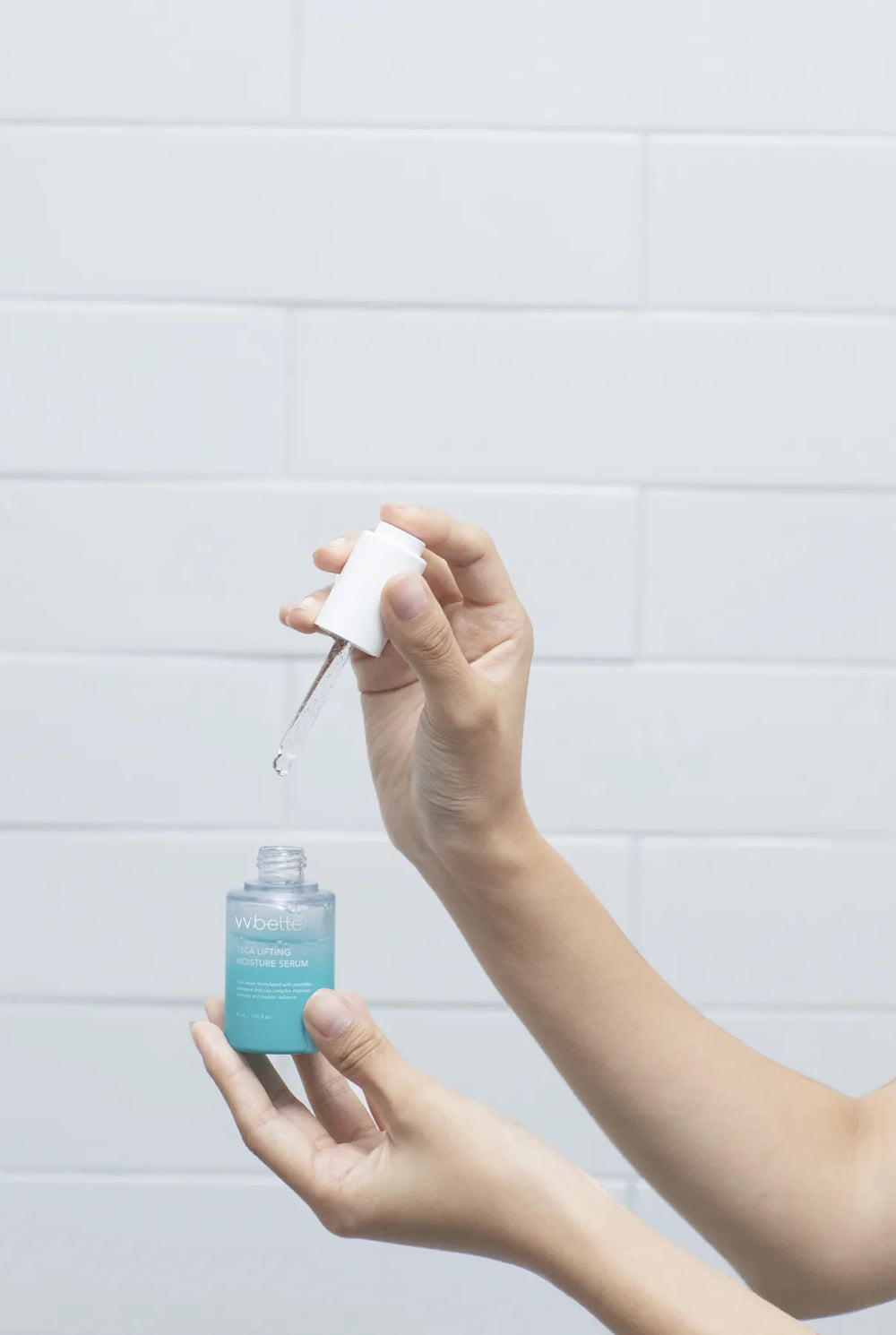 A hand squeezing the Teca Lifting Moisture Serum dropper