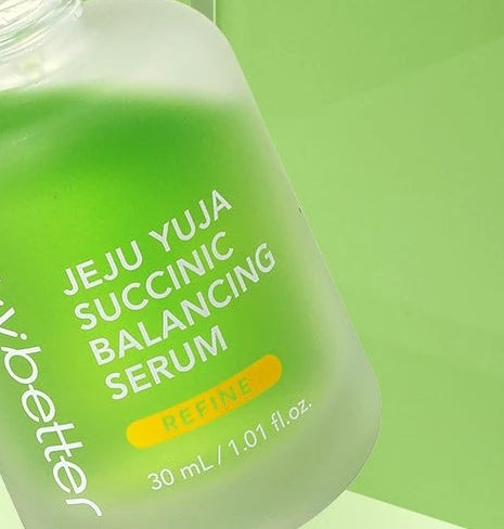 Open Jeju Yuja Succinic Balancing Serum bottle on a pale green background