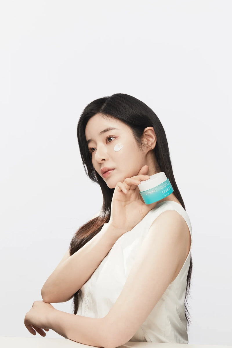 Model holding a Teca Lifting Moisture Cream jar next to her face with a dab of cream on her cheek