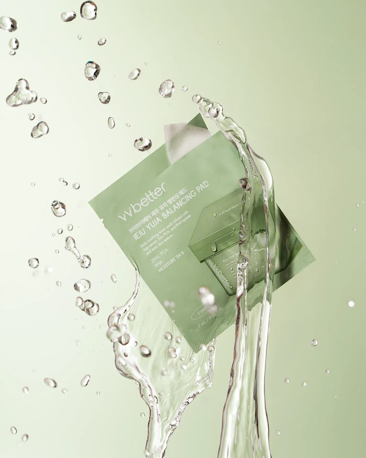 Sealed Jeju Yuja Balancing Pad mini pouch with water splashing around it on a light-green background
