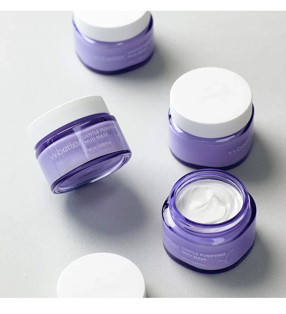 Several purple jars of Gentle Purifying Mud Mask, one open with white clay inside