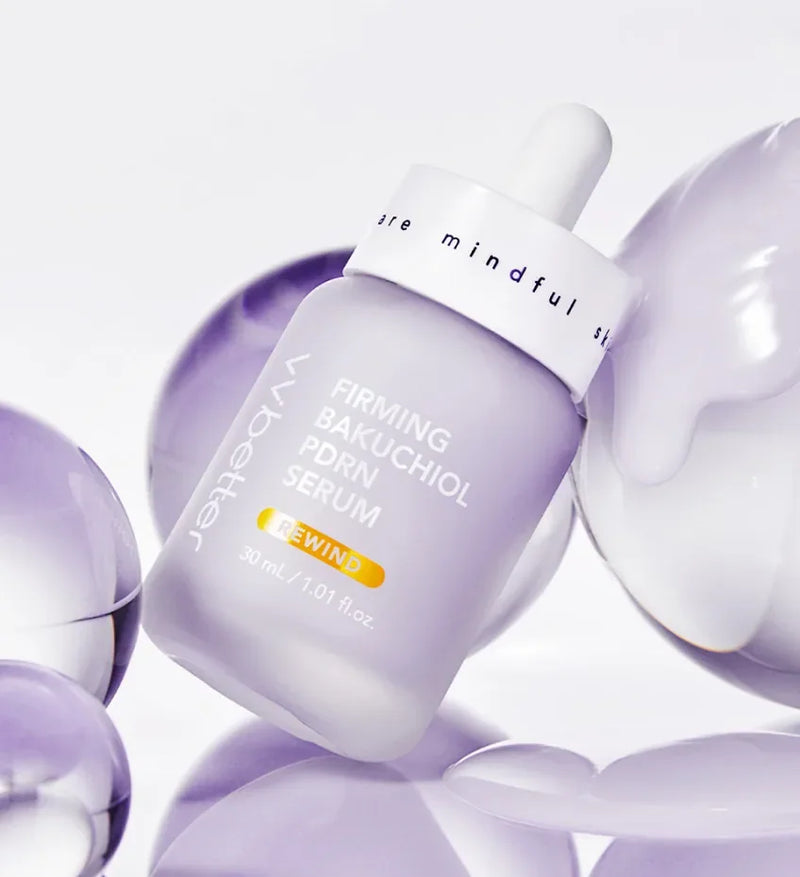 A lilac Firming Bakuchiol PDRN Serum bottle resting among glossy translucent lilac spheres