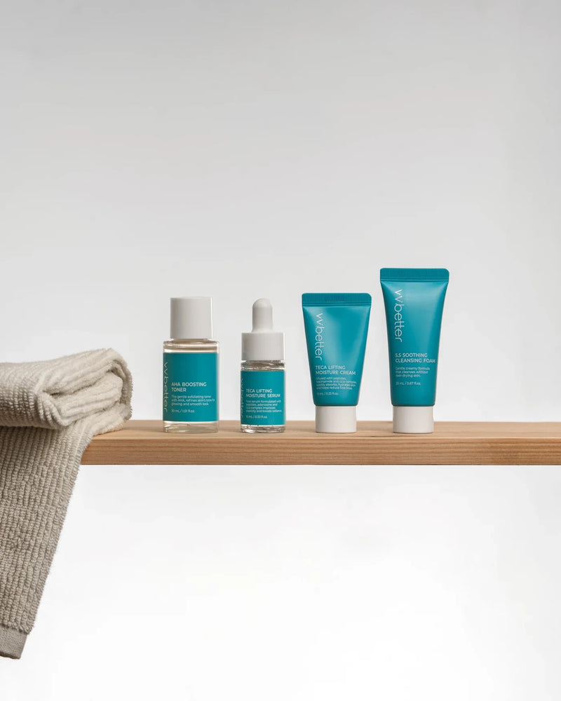 Four Travel Kit Blue minis on a wooden shelf beside a folded towel
