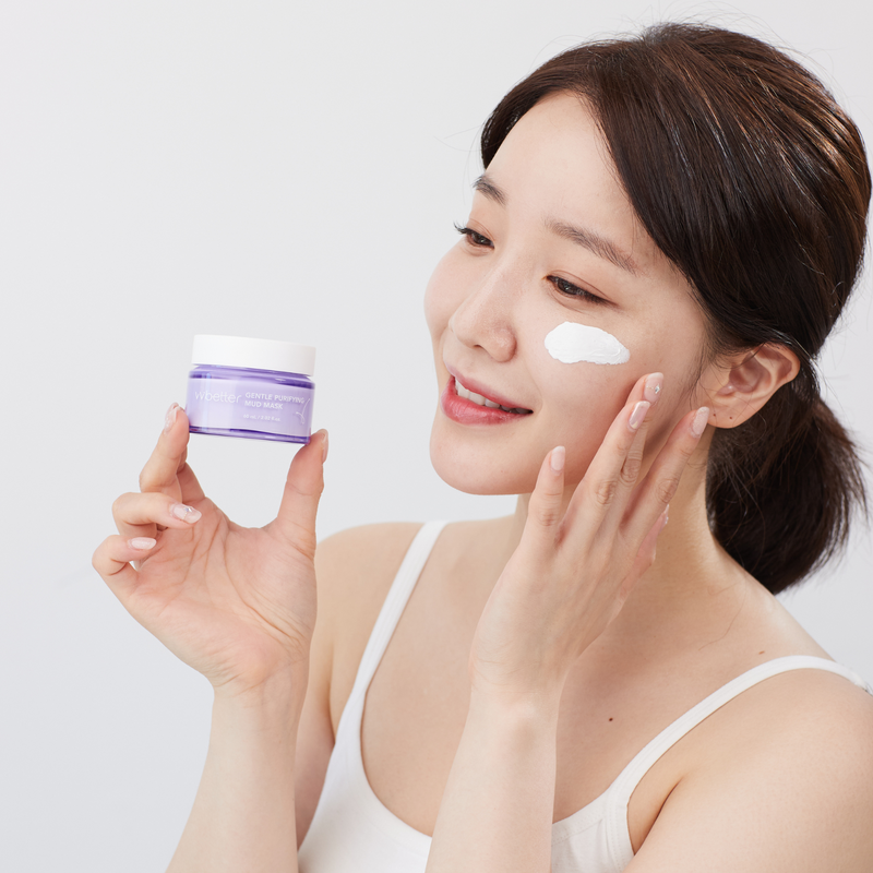 Gentle Purifying Mud Mask — model holding the jar with a swatch of clay on her cheek, how to use
