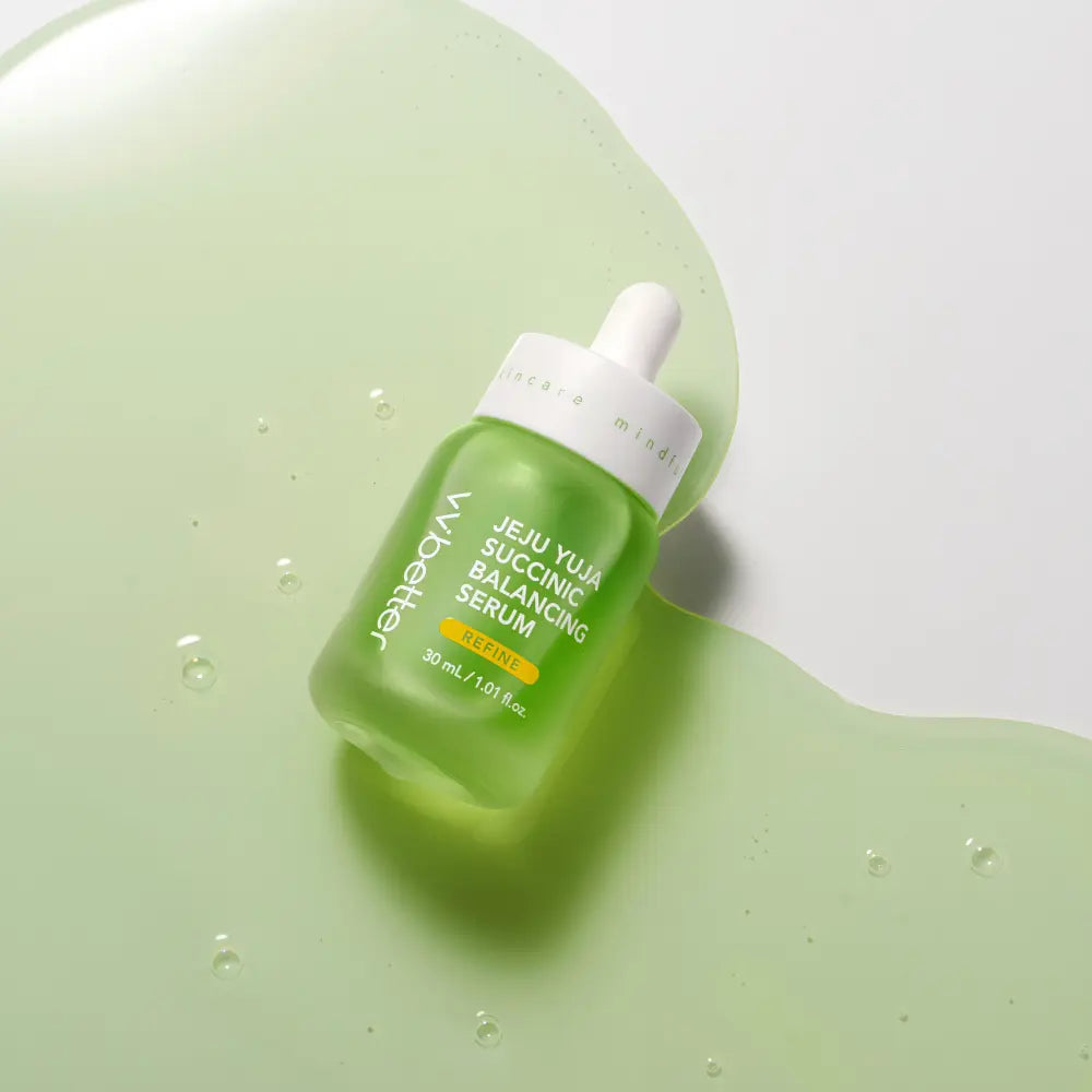 Jeju Yuja Succinic Balancing Serum — bottle lying in a pool of green serum, overhead view