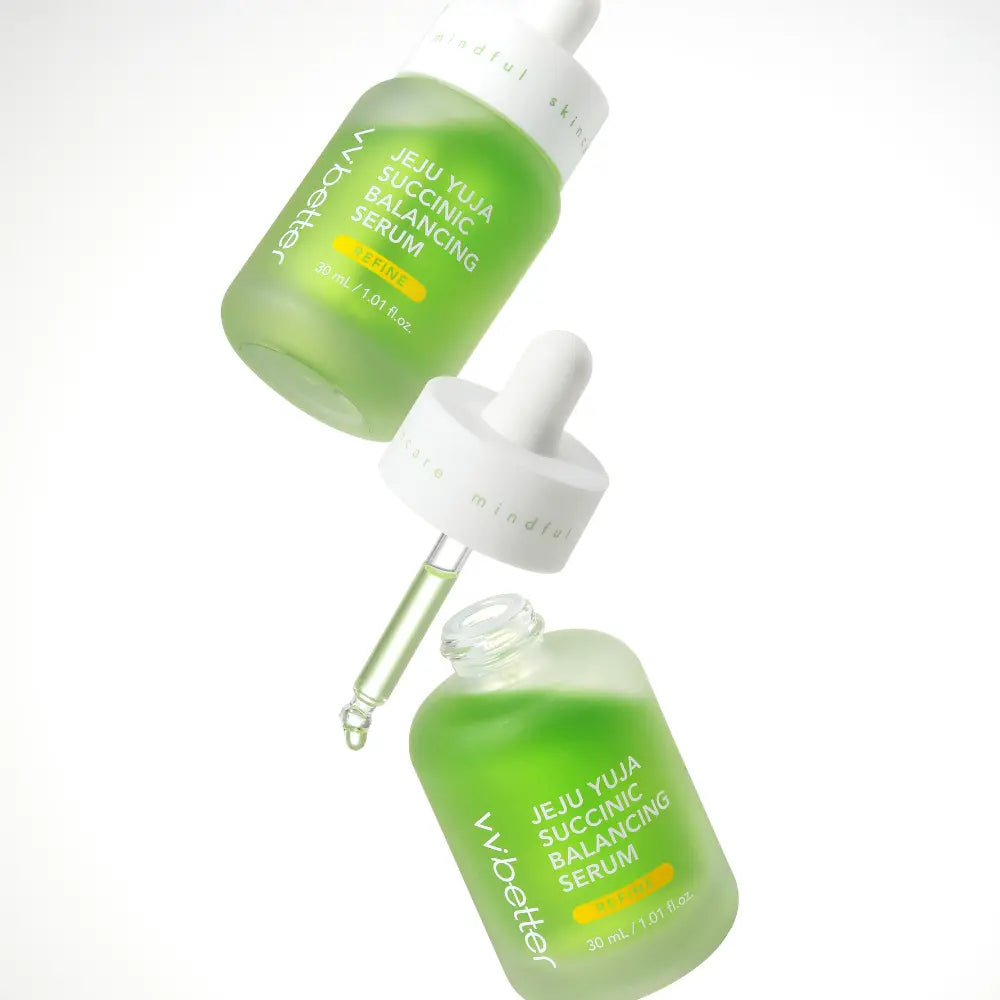 Jeju Yuja Succinic Balancing Serum — two bottles and an open dropper suspended against white, angle view
