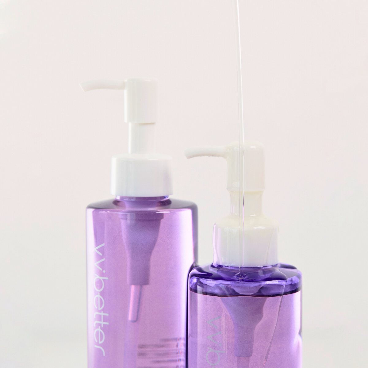 Gentle Deep Cleansing Oil — full-size and smaller pump bottles with a thread of oil, angle view