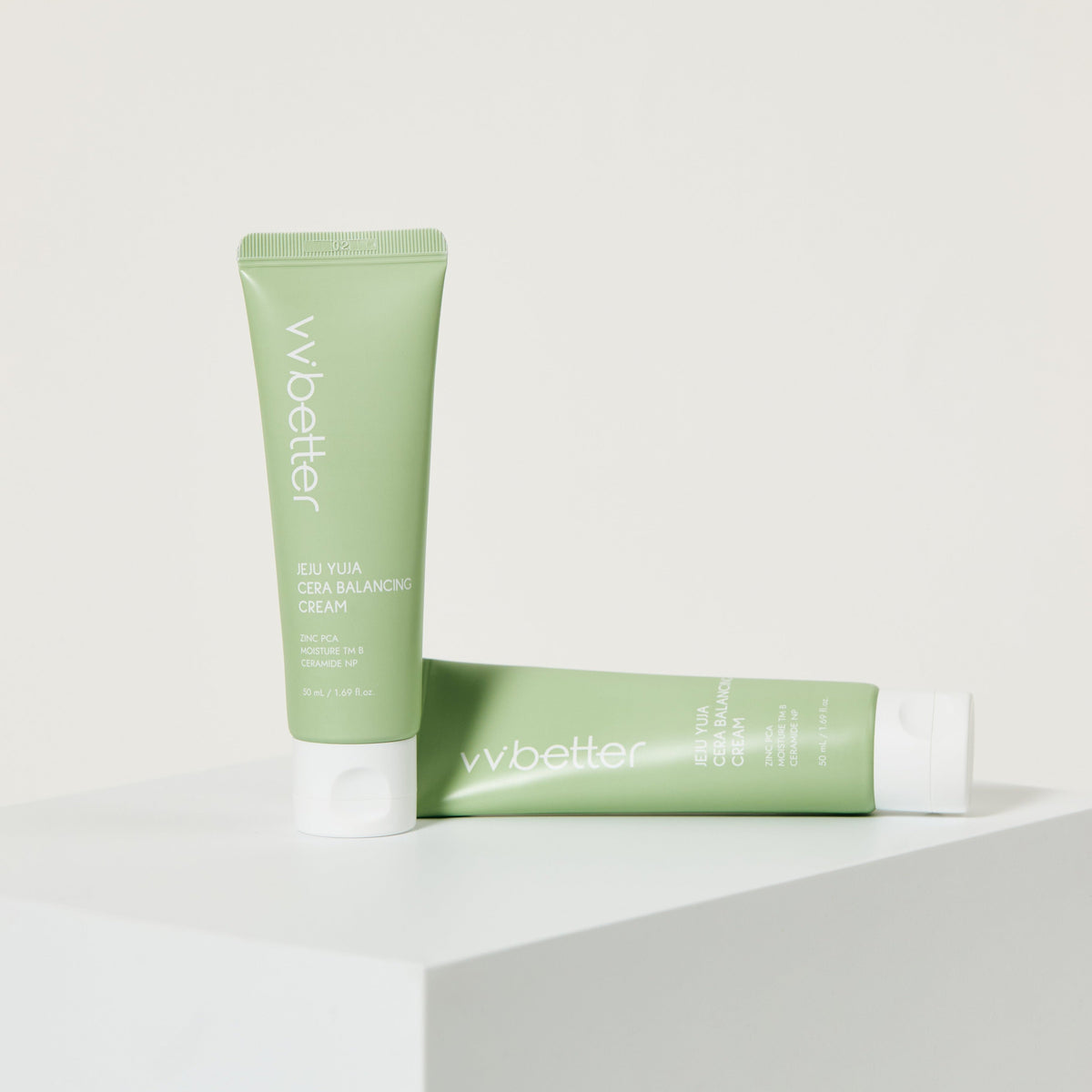 Jeju Yuja Cera Balancing Cream — two tubes on a white pedestal, one standing and one lying