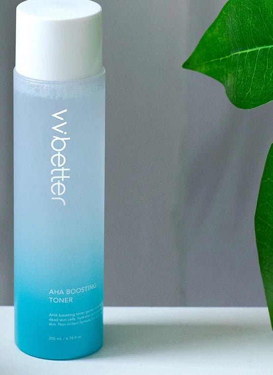AHA Boosting Toner bottle beside a white towel and a green leaf