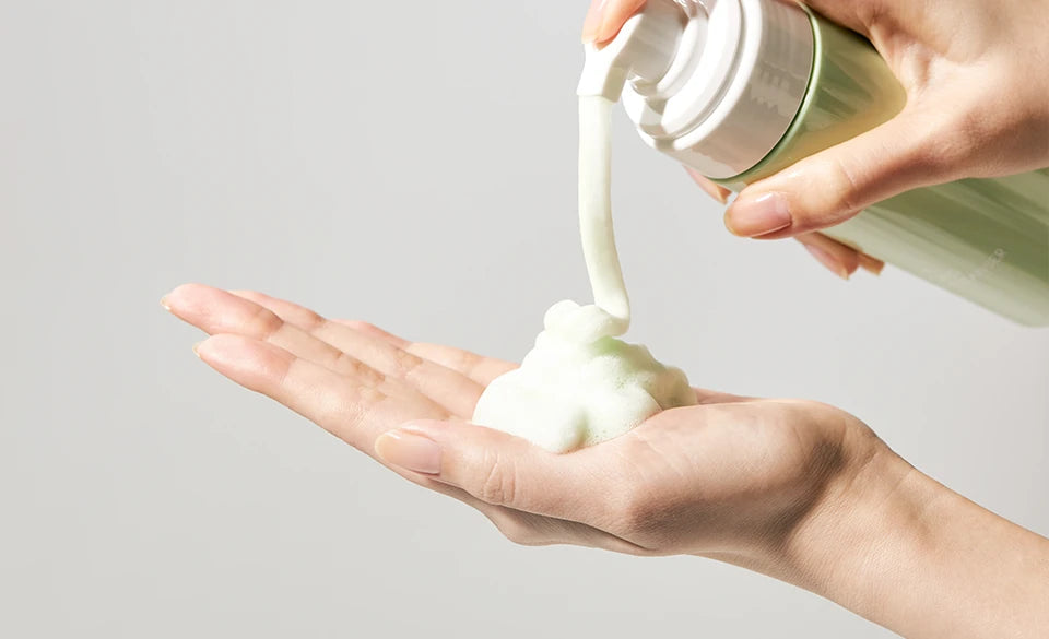 Hand pumping pale-green foam from the Jeju Yuja Balancing Bubble Cleanser into an open palm