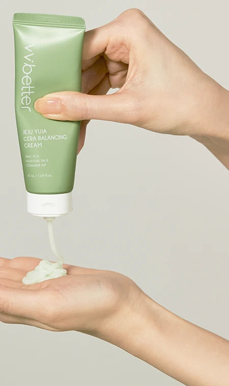 Hand squeezing pale-green gel cream from the Jeju Yuja Cera Balancing Cream tube into a palm
