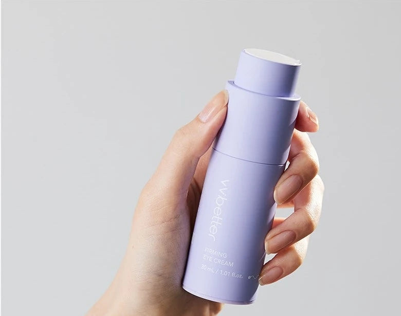 Hand holding the Firming Eye Cream bottle against a grey background
