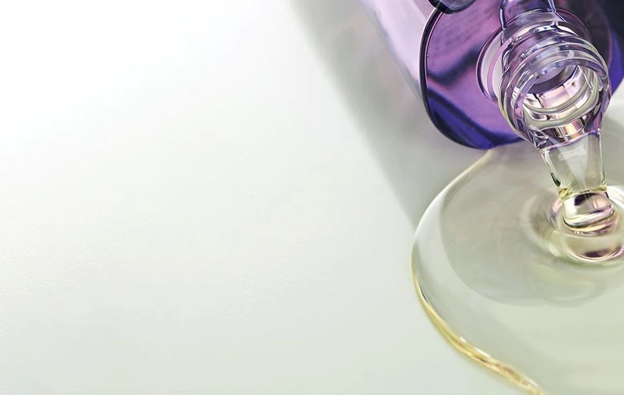 Bottle neck pouring cleansing oil into a puddle