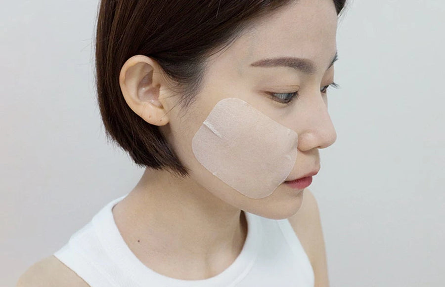 Woman wearing one pad on her cheek as a quick mask pack