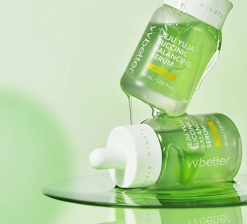 Two VVBETTER Jeju Yuja Succinic Balancing Serum bottles, the upper one dripping serum onto the lower one in a pool of green serum