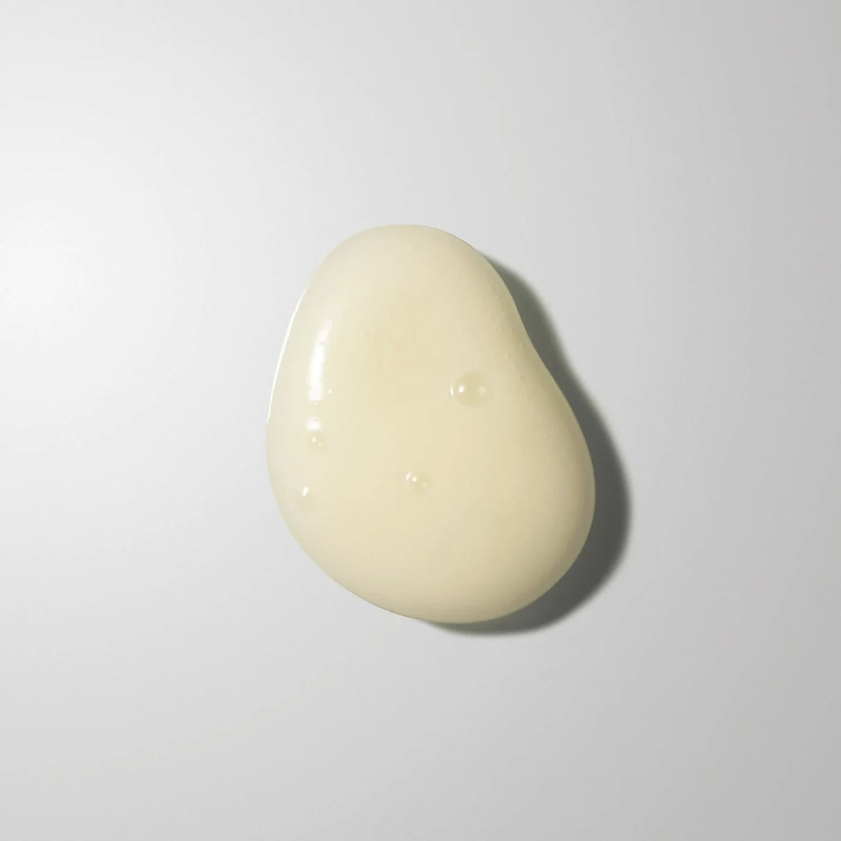 A soft, glossy swatch of the REGLOW Vita C TRX serum, which pairs glutathione with a vitamin C derivative, on a pale grey background