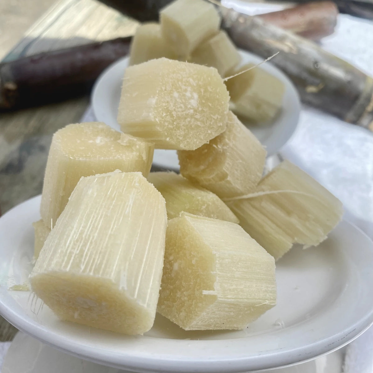 Peeled pieces of fresh sugarcane, the traditional source of glycolic acid, on a white plate