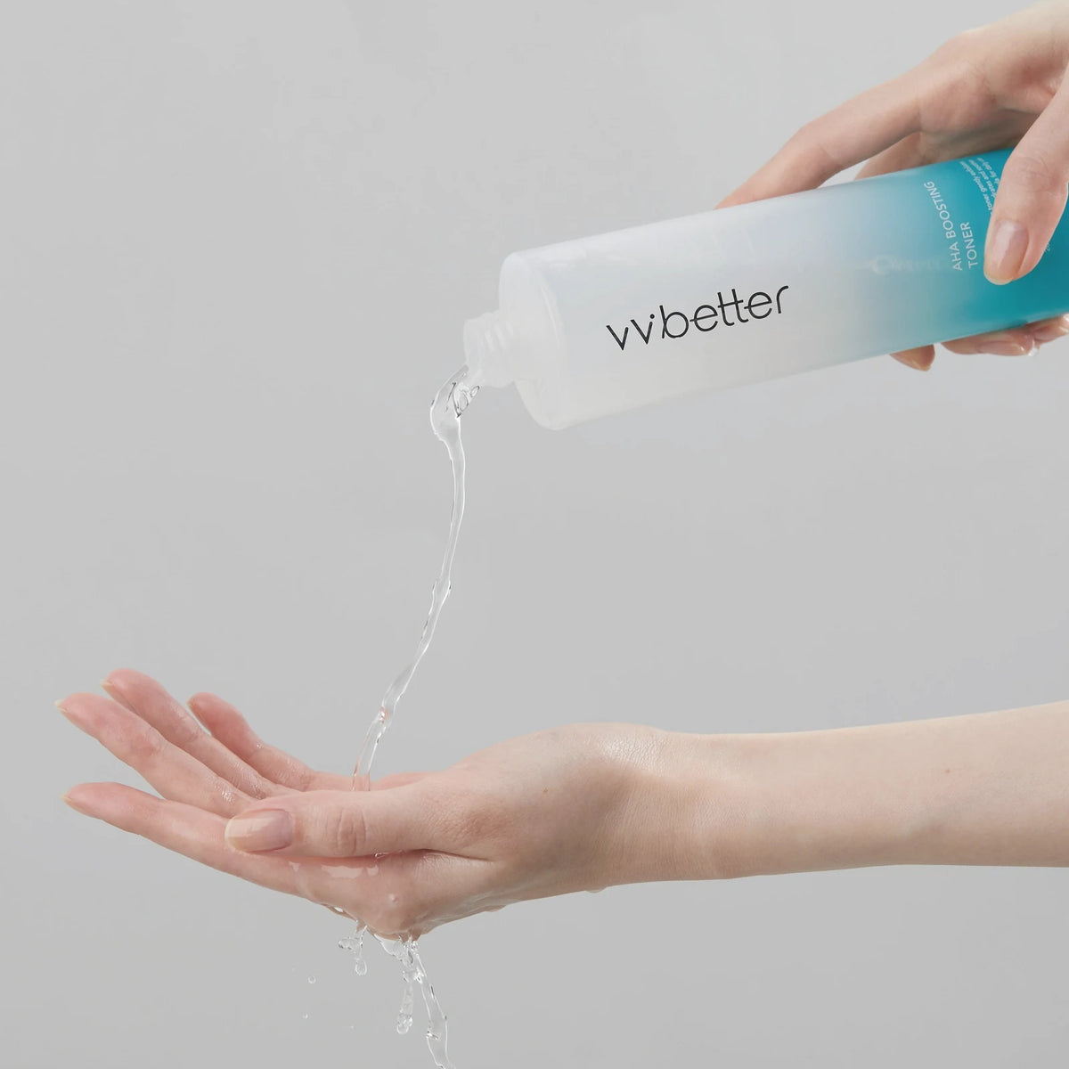Clear AHA Boosting Toner, made with lactic acid, poured from the bottle into an open palm