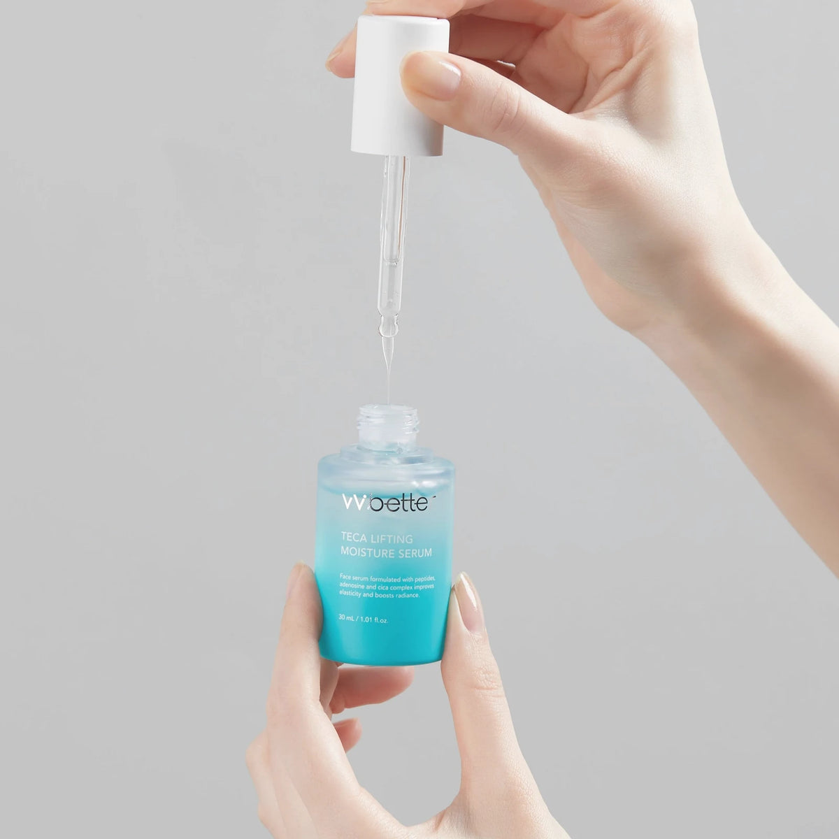 Hands lifting the glass dropper out of the Teca Lifting Moisture Serum bottle, a serum with 2% niacinamide, on a light grey background