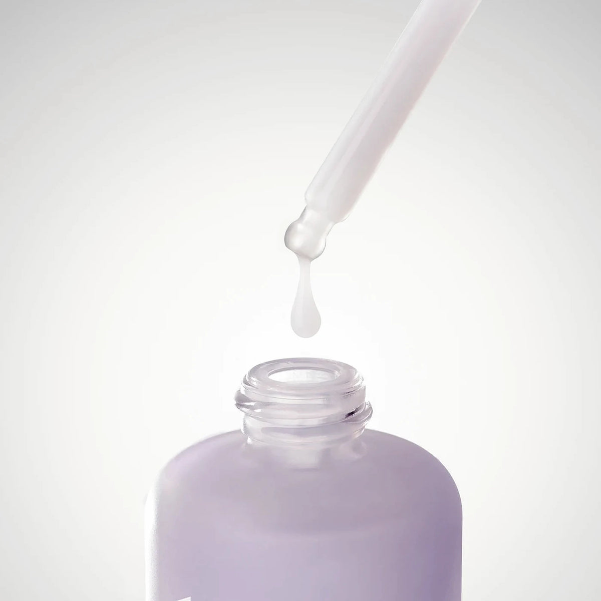 A drop of Firming Bakuchiol PDRN Serum falling from the glass dropper into the lilac REWIND bottle