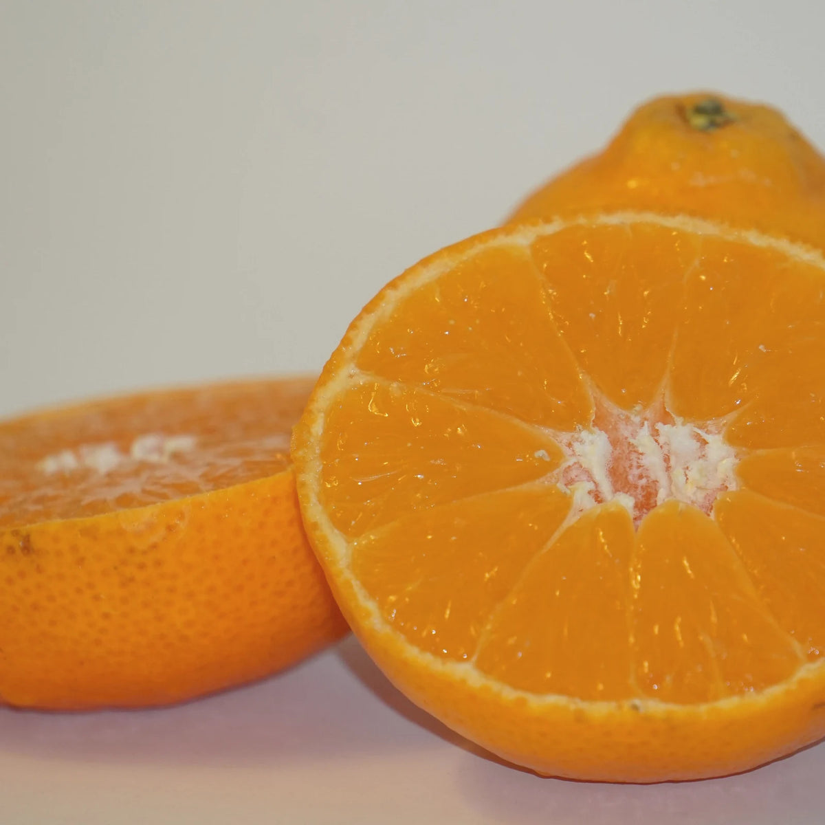 Two halves of a fresh orange, a classic source of vitamin C, on a pale background
